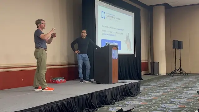 two men standing on the stage presenting the talk